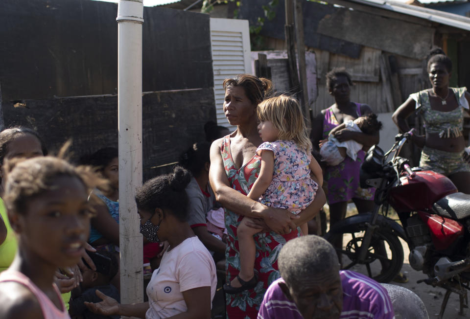 Women and children wait for donated food distributed by the the Covid Without Hunger organization in the Jardim Gramacho slum of Rio de Janeiro, Brazil, Saturday, May 22, 2021. Inflation is climbing at its fastest pace since 2016, at 6.8%, but over the past 12 months the cost of staple foods rose between 18% and 57%. (AP Photo/Silvia Izquierdo)