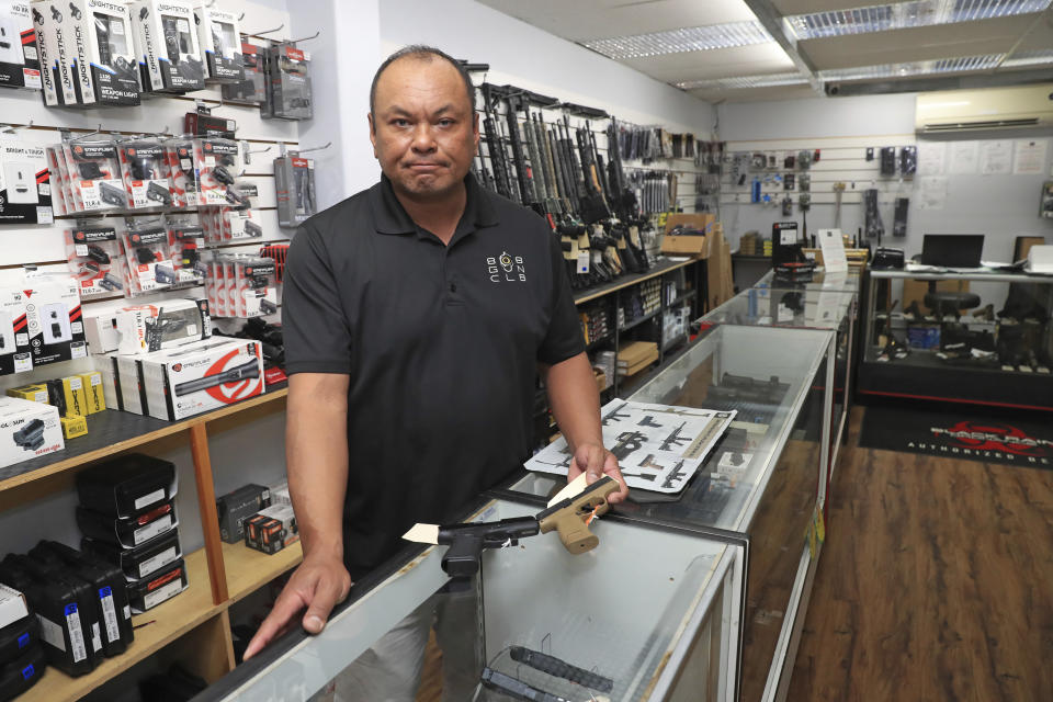 Tom Tomimbang, managing partner at the 808 Gun Club, shows off several small handguns inside his shop, Thursday, June, 23, 2022 in Honolulu. (AP Photo/Marco Garcia)