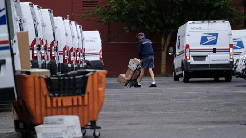 A United States Postal Service (USPS) worker loads mail into a truck to be delivered.