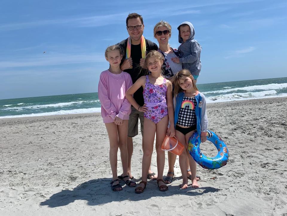 A family of 6 poses for a picture on the beach.