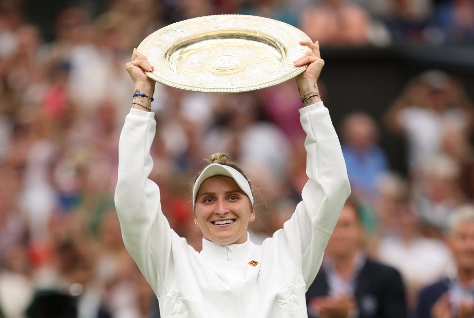 Marketa Vondrousova lifts the trophy after winning the WImbledon final.