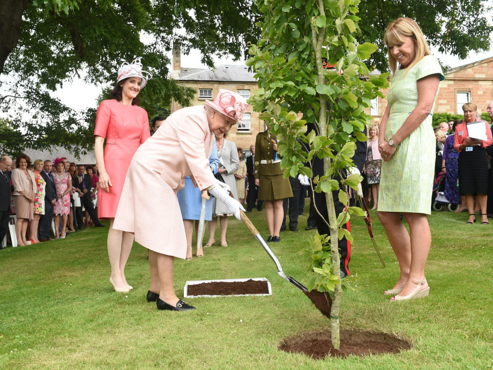 BELFAST, NORTHERN IRELAND - JUNE 24:  (EDITORIAL USE ONLY, NO SALES) In this handout image provided by Harrison Photography, Queen Elizabeth II pictured with the Secretary of State Theresa Villiers (L) planting a tree at a Garden Party in Hillsborough Castle on June 24, 2014 in Belfast, Northern Ireland. The Royal party are visiting Northern Ireland for three days.  (Photo by Simon Graham/Harrison Photography via Getty Images)