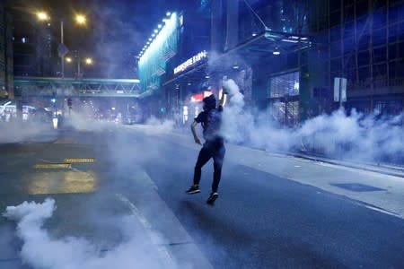 An anti-extradition bill protester throws a tear gas cartridge during clashes with police in Sham Shui Po in Hong Kong