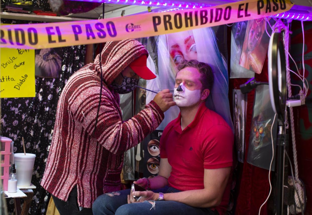 A tourist has makeup done ahead of Day of the Dead on Oct. 30, 2021, in Mexico City. <a href="https://www.gettyimages.com/detail/news-photo/tourist-is-having-makeup-done-as-a-skull-in-a-costume-news-photo/1350360186?adppopup=true" rel="nofollow noopener" target="_blank" data-ylk="slk:Alfredo Martinez/Getty Images;elm:context_link;itc:0;sec:content-canvas" class="link ">Alfredo Martinez/Getty Images</a>