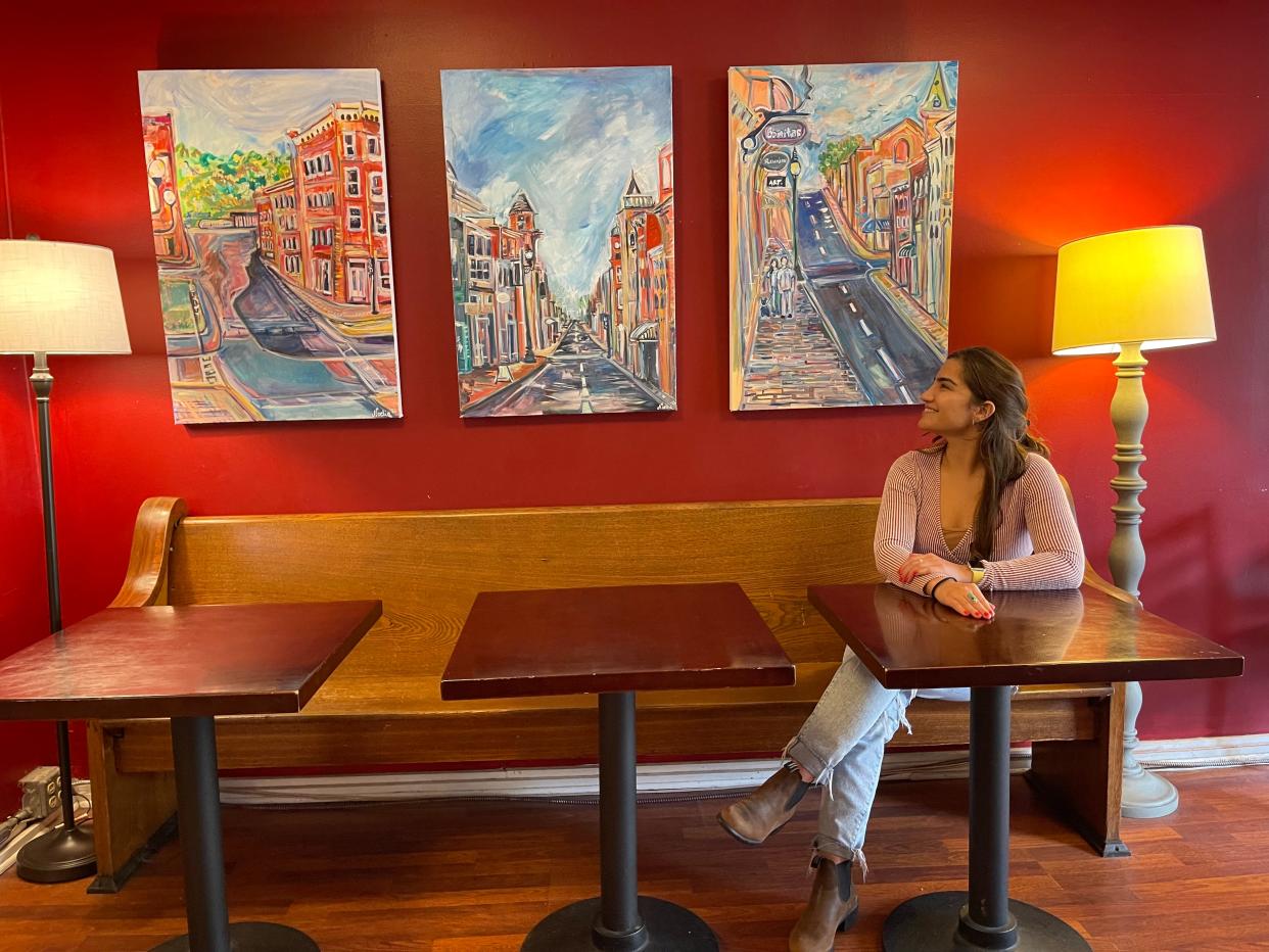 Artist Noelia Nuñez sits alongside her first downtown business display at By & By coffee in Staunton.