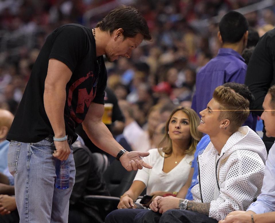 Singer Justin Bieber, right, talks with actor Mark Wahlberg as he watches the Los Angeles Clippers play the Oklahoma City Thunder in the second half of Game 4 of the Western Conference semifinal NBA basketball playoff series, Sunday, May 11, 2014, in Los Angeles. (AP Photo/Mark J. Terrill)