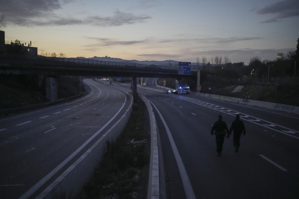 Police walk away from a farmers' highway barricade in Aix-en-Provence, southern France, Tuesday, Jan. 30, 2024. France's protesting farmers encircled Paris with traffic-snarling barricades Monday, using hundreds of lumbering tractors and mounds of hay bales to block highways leading to France's capital to pressure the government over the future of their industry. (AP Photo/Daniel Cole)