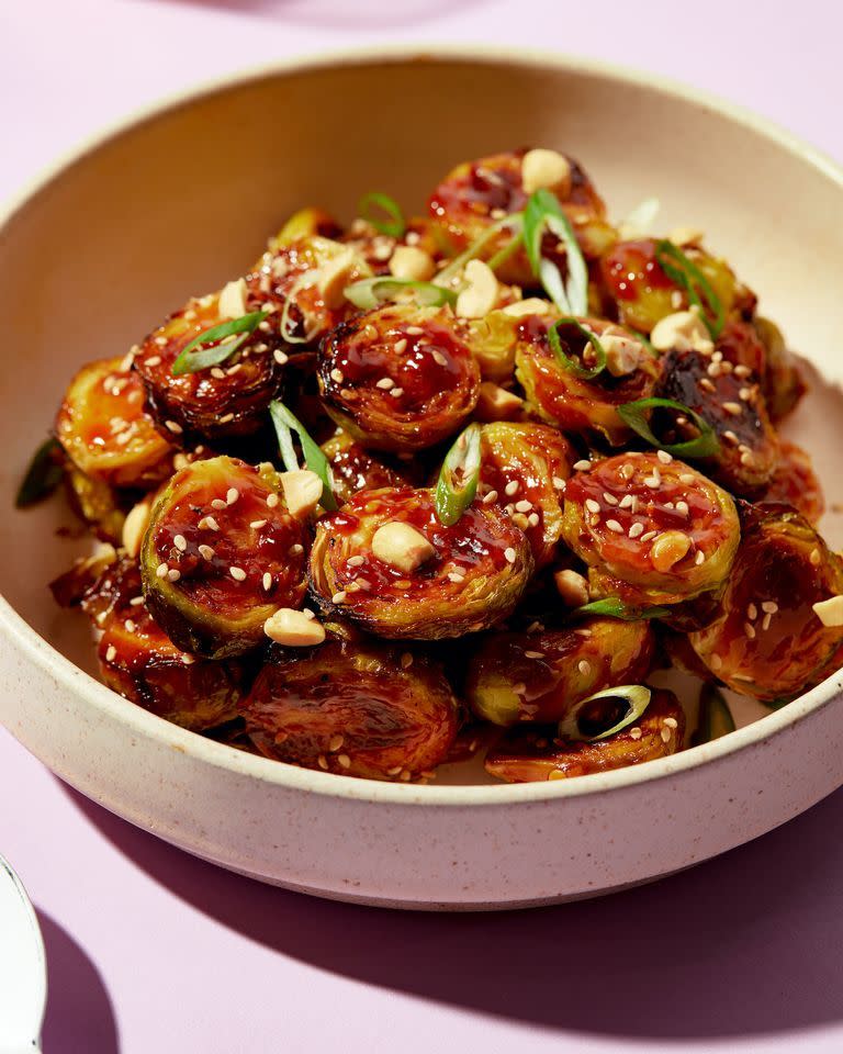 kung pao brussels topped with sesame seeds, peanuts, and scallions