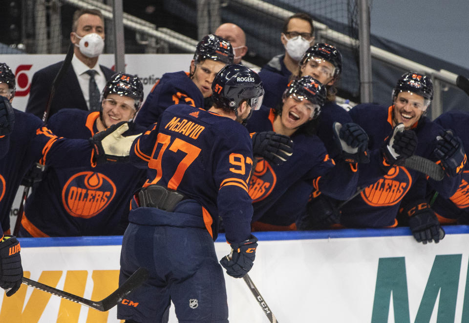 Edmonton Oilers' Connor McDavid (97) celebrates his 100th point this season, against the Vancouver Canucks during the second period of an NHL hockey game Saturday, May 8, 2021, in Edmonton, Alberta. (Jason Franson/The Canadian Press via AP)