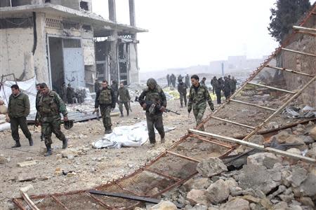 Syrian army soldiers loyal to Syria's President Bashar al-Assad walk with their weapons in the Aleppo town of Naqaren, after claiming to have regained control of the town, January 14, 2014. REUTERS/George Ourfalian