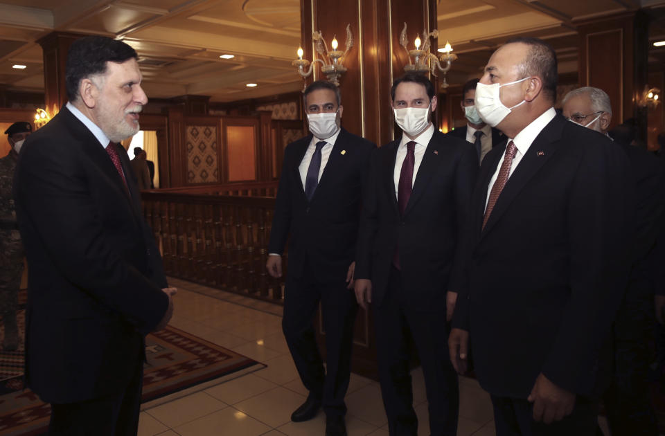 Turkey's Foreign Minister Mevlut Cavusoglu, right, and Fayez Sarraj, left, the head of Libya's internationally-recognized government, greet each other before their talks in Tripoli, Libya, Wednesday, June 17, 2020. Turkish Finance Minister Berat Albayrak, second right, and Turkey's Intelligence Chief Hakan Fidan stand in the background. (Fatih Aktas/Turkish Foreign Ministry via AP, Pool)