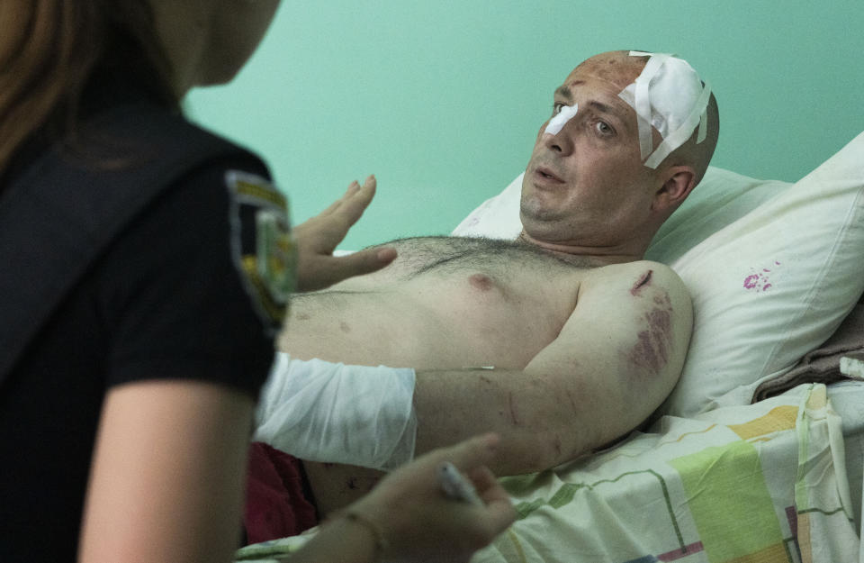 A police officer writes a report as a man wounded by the Russian deadly rocket attack at a shopping centre tells her about the attack in a city hospital in Kremenchuk in Poltava region, Ukraine, Tuesday, June 28, 2022. (AP Photo/Efrem Lukatsky)