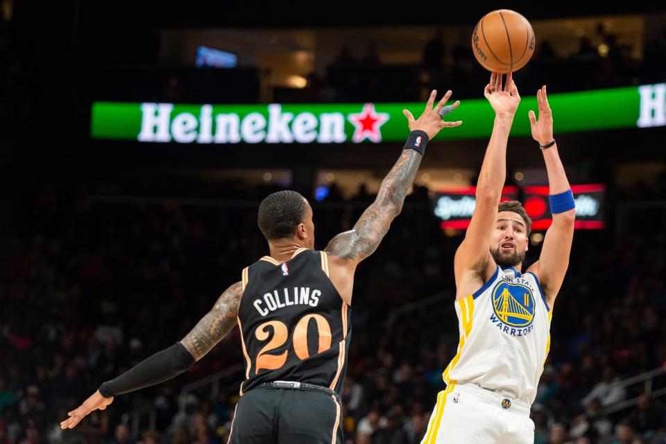 Golden State Warriors guard Klay Thompson, right, shoots a 3-pointer over Atlanta Hawks forward John Collins during a NBA game March 17 in Atlanta.
