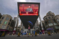 People walk past a large video screen outside a shopping mall showing Chinese President Xi Jinping speaking during an event to commemorate the 100th anniversary of China's Communist Party at Tiananmen Square in Beijing, Thursday, July 1, 2021. China's ruling Communist Party is marking the 100th anniversary of its founding with speeches and grand displays intended to showcase economic progress and social stability to justify its iron grip on political power. (AP Photo/Andy Wong)