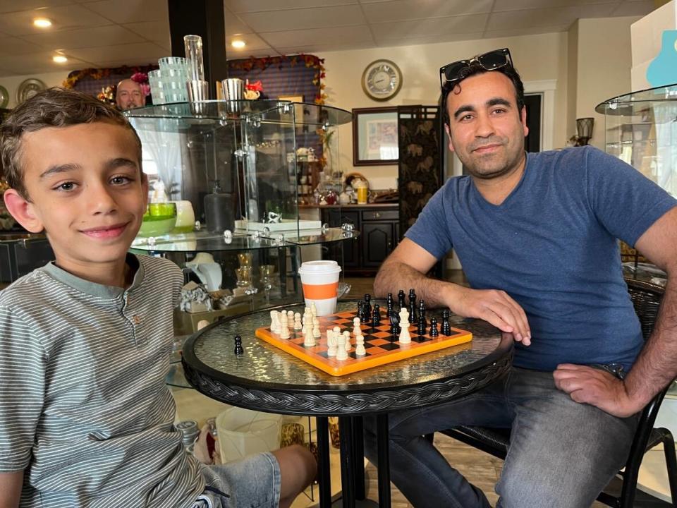 Eight-year-old Ouws Alhasoun and his father Ghazi enjoy a game of chess at the Association for New Canadians' 'Chess and Chat' event at the Gordon High Lander Tea Room in Grand Falls-Windsor. (Melissa Tobin/CBC - image credit)