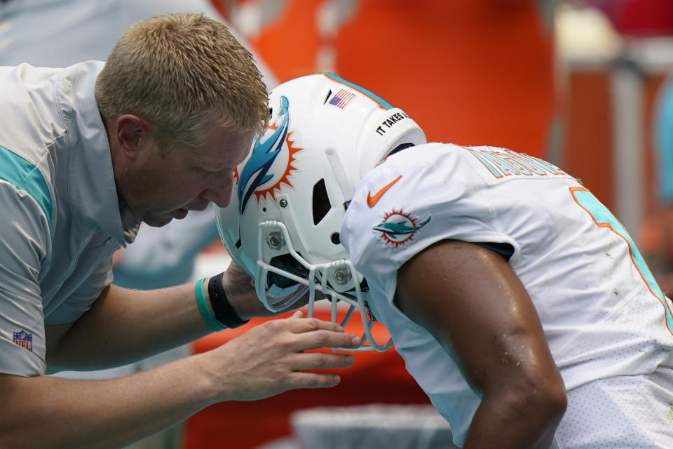 A member of the team staff assists Miami Dolphins quarterback Tua Tagovailoa (1) after he left the field injured during the first half of an NFL football game against the Buffalo Bills, Sunday, Sept. 19, 2021, in Miami Gardens, Fla. (AP Photo/Wilfredo Lee)