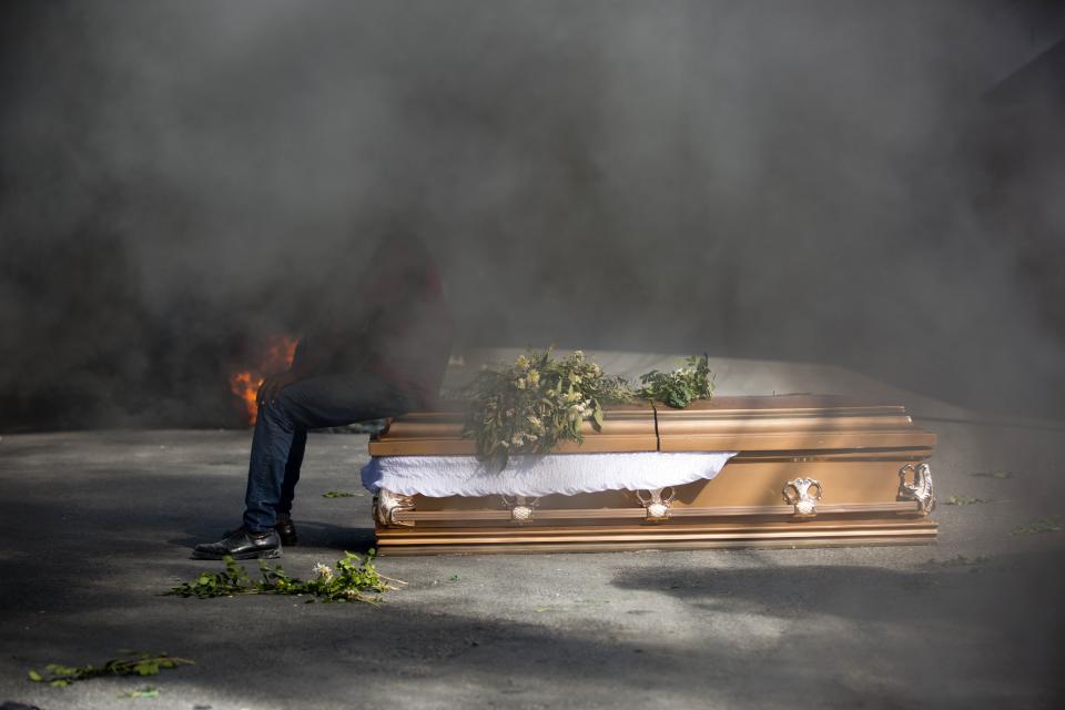 A demonstrator sits on the coffin containing the body of a protester who was killed during previous protests in Port-au-Prince, Haiti, Monday, March 4, 2019. Protesters are angry about skyrocketing inflation and the government's failure to prosecute embezzlement from a multi-billion Venezuelan program that sent discounted oil to Haiti. (AP Photo/Dieu Nalio Chery)