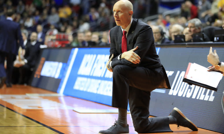 Louisville Cardinals head coach Chris Mack kneeling on the sideline during a game.