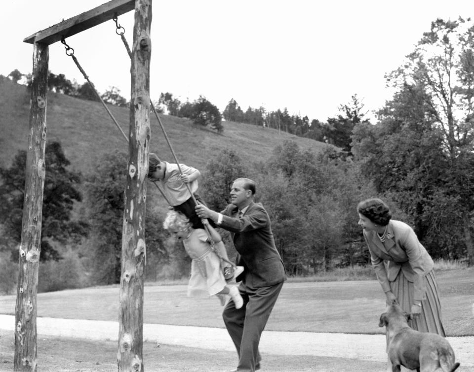 Prince Charles and Princess Anne being pushed on a swing by their father, the Duke of Edinburgh, with their mother Queen Elizabeth II looking on, in the grounds of Balmoral.   (Photo by PA Images via Getty Images)