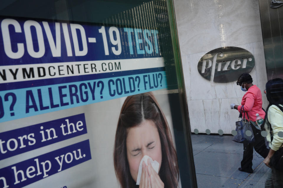  People wearing masks walks past a Pfizer sign outside their headquarters in New York City. Pharmaceutical company Pfizer announced positive early results on its COVID-19 vaccine trial and has proven to be 90\% effective in preventing infection of the virus. (Photo by John Nacion / SOPA Images/Sipa USA) 