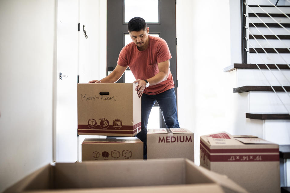 Man lifting moving boxes at new home