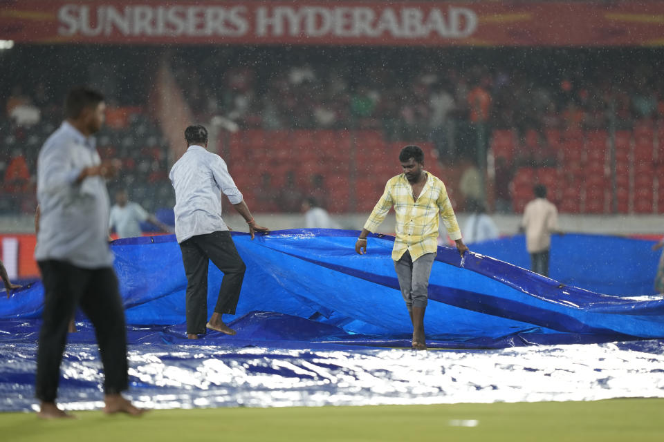 Ground staff cover the pitch as it rains before the scheduled start of the Indian Premier League cricket match between Gujrat Titans and Sunrisers Hyderabad forcing delay in the start of the match in Hyderabad, India, Thursday, May 16, 2024. (AP Photo /Mahesh Kumar A.)