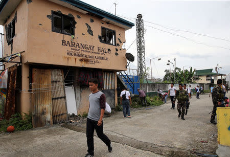 Local government workers and soldiers walk past a battle damaged town hall after government troops cleared the area from pro-Islamic State militant groups inside the war-torn Marawi city, southern Philippines October 19, 2017. REUTERS/Romeo Ranoco