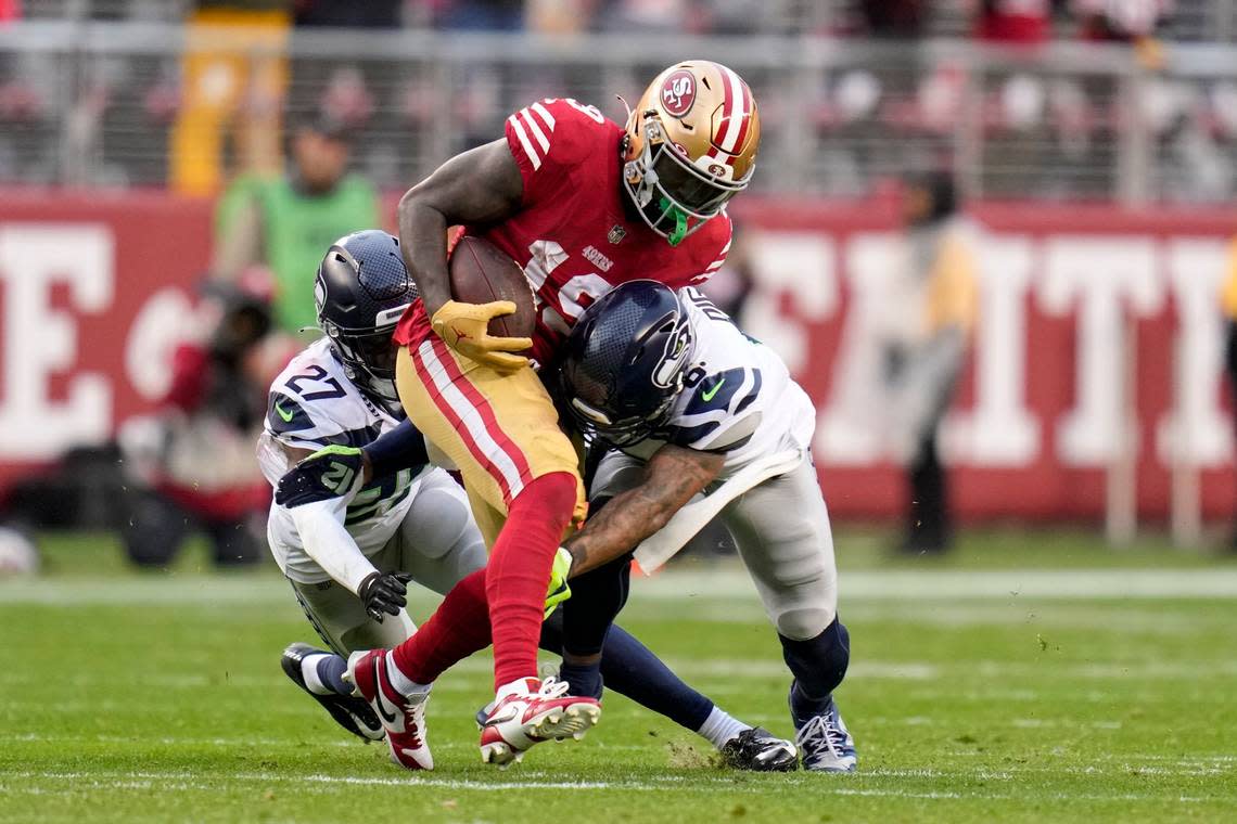 San Francisco 49ers wide receiver Deebo Samuel (19) runs against Seattle Seahawks cornerback Tariq Woolen (27) and safety Quandre Diggs (6) during the second half of an NFL wild card playoff football game in Santa Clara, Calif., Saturday, Jan. 14, 2023. (AP Photo/Godofredo A. Vásquez)