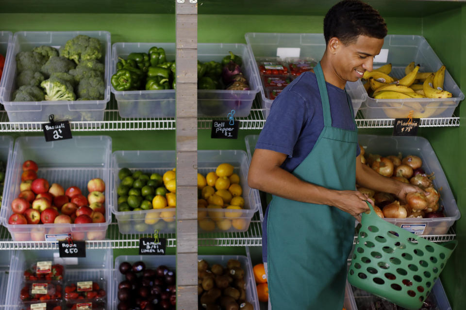 In this Tuesday, Aug. 20, 2019 photo, volunteer Xavier Lopez helps a customer select fruits and vegetables at the Fresh MARTA Market at the West End transit station in Atlanta. The Metropolitan Atlanta Rapid Transit Authority and the Atlanta nonprofit Community Farmers Markets partner to run the stands, which provide a healthy food source for people living in food deserts.(AP Photo/Andrea Smith)