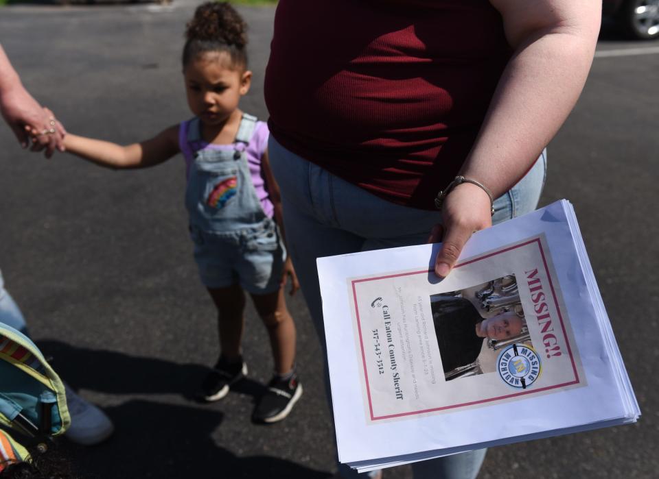 A woman holds missing person signs Thursday, May 11, 2023, where she and about 10 others searched the area looking for Richard Johnson near Delta Square Apartments and Plumtree Apartments in Lansing. He was last seen leaving Plumtree Apartments on May 7, and resides at the neighboring Delta Square Apartments in Delta Township.