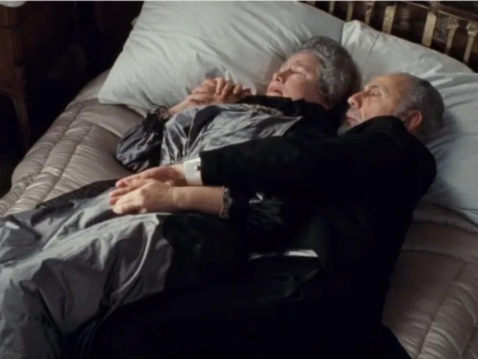 A scene from James Cameron's "Titanic" where an elderly couple are seen lying on a bed together as their room begins to flood with water.