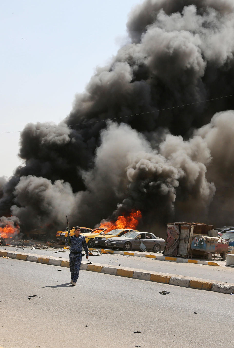 An Iraqi policeman rushes to the site moments after one in a series of bombs hit the Shiite stronghold of Sadr City, in Baghdad, Iraq, Tuesday, May 13, 2014. A wave of car bombings in mainly Shiite areas of Baghdad killed tens on Tuesday, officials said. (AP Photo/Karim Kadim)