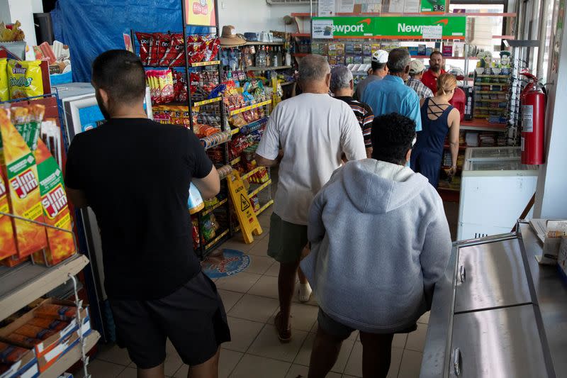 People line up to pay for fuel and groceries at a gas station after an earthquake in Guanica