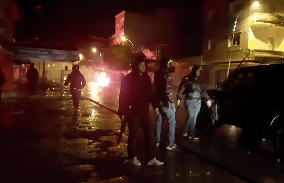 Police officers face demonstrators during clashes in Siliana, Tunisia, Saturday, Jan.16, 2021. Police used tear gas to disperse violent protests led by disgruntled youths in several Tunisian cities Saturday night to Sunday, including in the capital Tunis and the seaside city of Sousse. Though the causes are unclear, Tunisians are angry that the North African country is on the verge of bankruptcy and has dire public services. (AP Photo/Hedi Sfar)