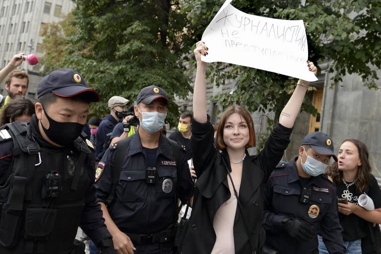 Policías rusos detienen a una periodista que lleva un cartel que dice: "No dejaremos de ser periodistas" en una protesta en Moscú