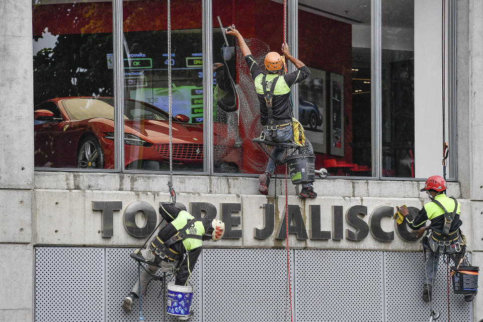 Workers clean the windows of the Ferrari dealership in Caracas, Venezuela, Wednesday, April 20, 2022. Venezuela lifted a ban on importing used cars in 2019, but years of hyperinflation and government controls left banks unwilling or unable to make car loans. (AP Photo/Matias Delacroix)