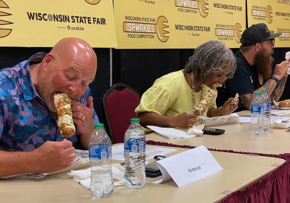 2022 Wisconsin State Fair Sporkies food competition judges Bill Mitchell, Dr. Stacia Thompson and Chef Adam Pawlak trying the Peño Pretzel Popper Brat from Gertrude’s Pretzels. The pretzel popper brat won first place.