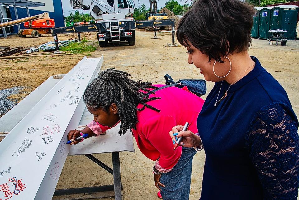 Hagerstown Mayor Tekesha Martinez signs the final beam for the new field house as former Mayor Emily Keller waits her turn.