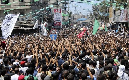 Palestinians carry the bodies of three senior Hamas commanders, who were killed in an Israeli air strike, during their funeral in Rafah in the southern Gaza Strip August 21, 2014. REUTERS/Ibraheem Abu Mustafa