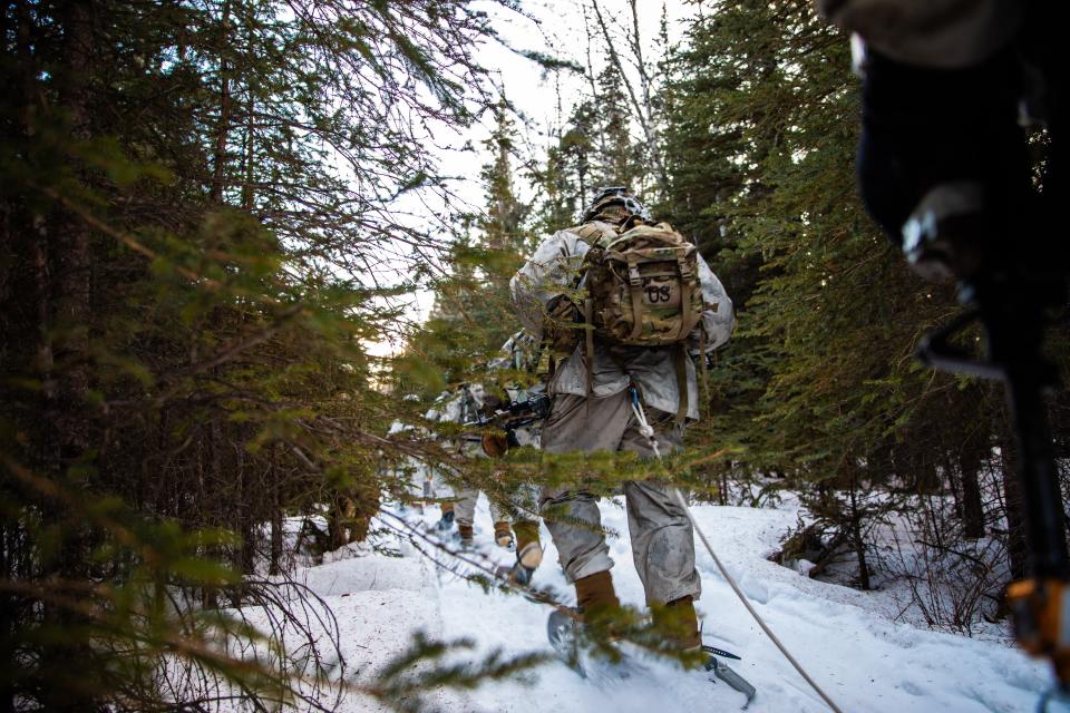 U.S. Soldiers, assigned to 1st Battalion, 5th Infantry Regiment, 1st Infantry Brigade Combat Team, 11th Airborne Division, carry equipment through a forest during Joint Pacific Multinational Readiness Center 24-02 at Donnelly Training Area, Alaska, Feb. 17, 2024.