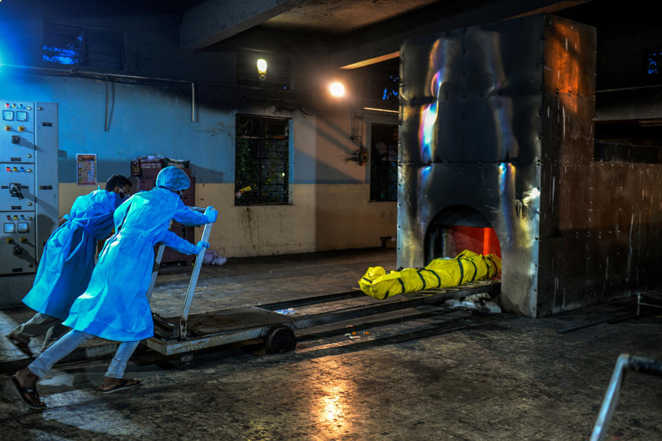 Workers push the body of a COVID-19 patient into the furnace of Yerawada crematorium in Pune on Aug. 11.<span class="copyright">Atul Loke for TIME</span>