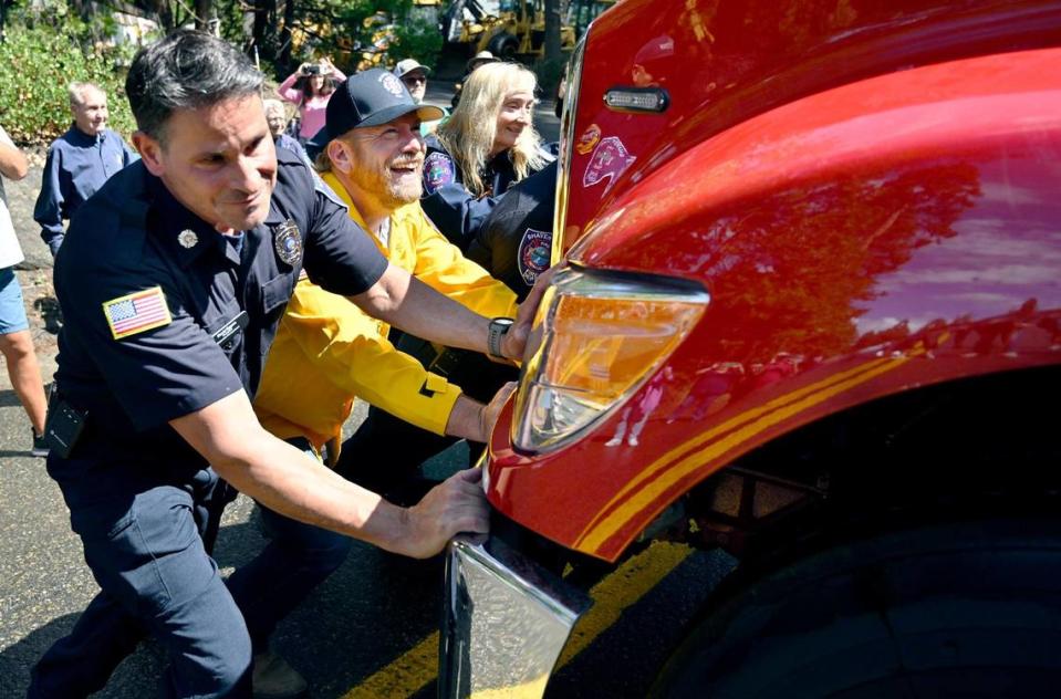 Shaver Lake firefighter David Eggers, left, with help from Fresno County Supervisor Nathan Magsig, right, help welcome a new fire engine E-260 into the Shaver Lake Volunteer Fire Department with a time-honored “push-in” tradition Thursday afternoon, Aug. 24, 2023 in Shaver Lake.