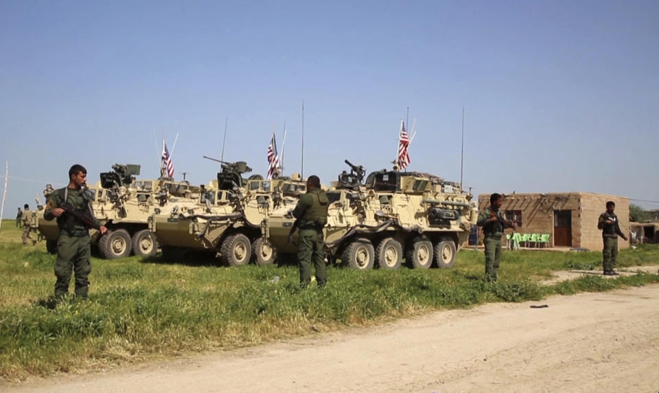 FILE -- In this April, 29, 2017 file image taken from video, shows Kurdish fighters of the People's Protection Units (YPG) standing guard as U.S. forces take up positions in the northern village of Darbasiyah, Syria. Syria’s Kurds have been America’s partner in fighting the Islamic State group for nearly four years. Now they are furious over an abrupt U.S. troop pull-back that exposes them to a threatened attack by their nemesis, Turkey. The surprise U.S. pull-back from positions near the Turkish border, which began Monday, Oct. 7, 2019, stung even more because the Kurds have been abandoned before by the U.S. and other international allies on whose support they'd pinned their aspirations. (AP Photo, File)