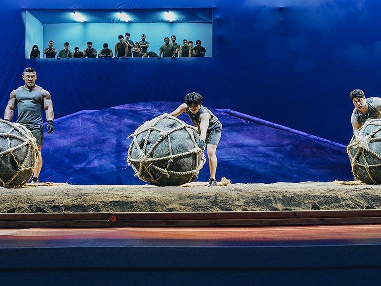 4 people getting ready to carry large rock