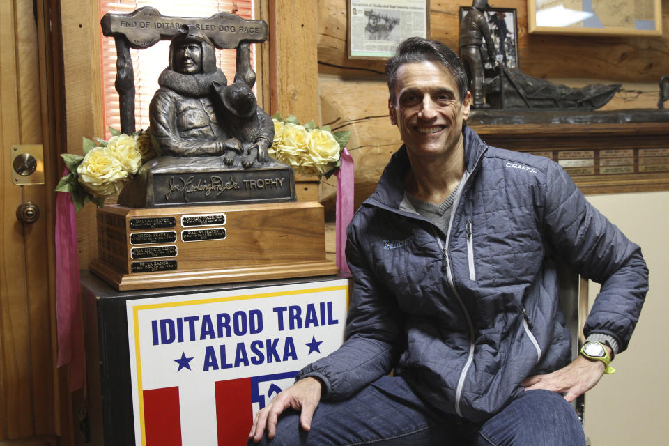 Rob Urbach, CEO of the Iditarod Trail Sled Dog Race, poses Feb. 10, 2022, in Wasilla, Alaska, next to the trophy that is presented to the winner of the world's most famous sled dog race. The Iditarod is returning to a sense of normalcy this year as the ceremonial start will again be held in Anchorage, Alaska, on Saturday, March 5, 2022, and the race will end about 10 days later in Nome, Alaska. The ceremonial start was canceled last year because of the pandemic, and the race started and finished north of Anchorage instead of traveling to Nome. (AP Photo/Mark Thiessen)