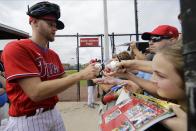 FILE - In this Feb. 14, 2020, file photo, Philadelphia Phillies' Zack Wheeler, left, gives autographs during a spring training baseball workout in Clearwater, Fla. Wheeler's last start before his 30th birthday could have come against his former team. Wheeler, who struck out 24% of the batters he faced last season with the Mets, left New York in free agency last winter for a $118 million, five-year deal with the NL East rival Phillies.(AP Photo/Frank Franklin II, File)