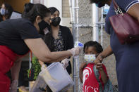 FILE - In this Sept. 9, 2020, file photo, a student has their temperature taken as they arrive for classes at the Immaculate Conception School while observing COVID-19 prevention protocols in The Bronx borough of New York. New York City has again delayed the planned start of in-person learning for most of the more than 1 million students in its public school system. Mayor Bill de Blasio announced Thursday, Sept. 17, that most elementary school students would do remote-only learning until Sept. 29. Middle and high schools would stay remote through Oct. 1. (AP Photo/John Minchillo)