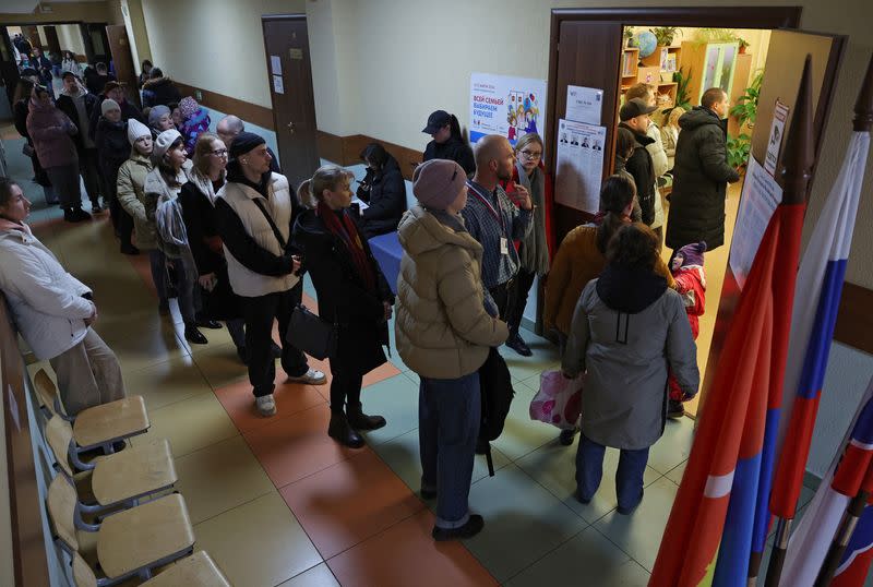 Varias personas hacen cola para entrar en un colegio electoral hacia el mediodía del último día de las elecciones presidenciales en la ciudad de Kudrovo