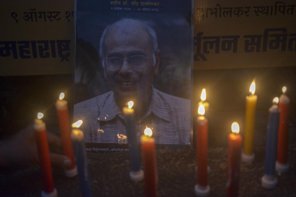 Members of the Maharashtra Andhashraddha Nirmulan Samiti, an organization dedicated to fighting superstition in India, lit candles near a photograph of anti-superstition activist Narendra Dabholkar during the candlelight vigil on the eve off his 10th death anniversary in Pune, India, Saturday, Aug 19, 2023. (AP Photo/ Shankar Narayan)