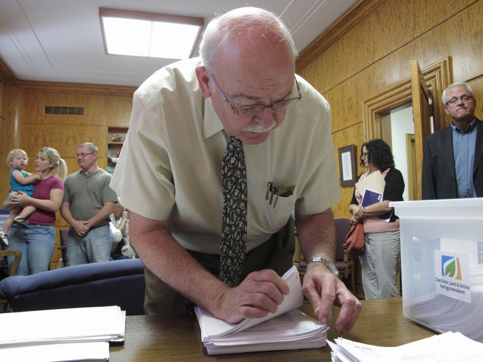 North Dakota Secretary of State Al Jaeger counts initiative petitions in his office in the North Dakota Capitol on Monday, Aug. 6, 2012. The citizen initiative, which was submitted Monday, would set aside part of North Dakota's oil tax collections for wildlife, wetlands and conservation projects. (AP Photo/Dale Wetzel)